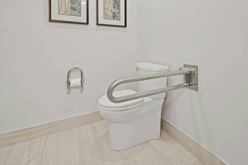 Hand holding a faucet over a walk-in tub installation in a renovated bathroom